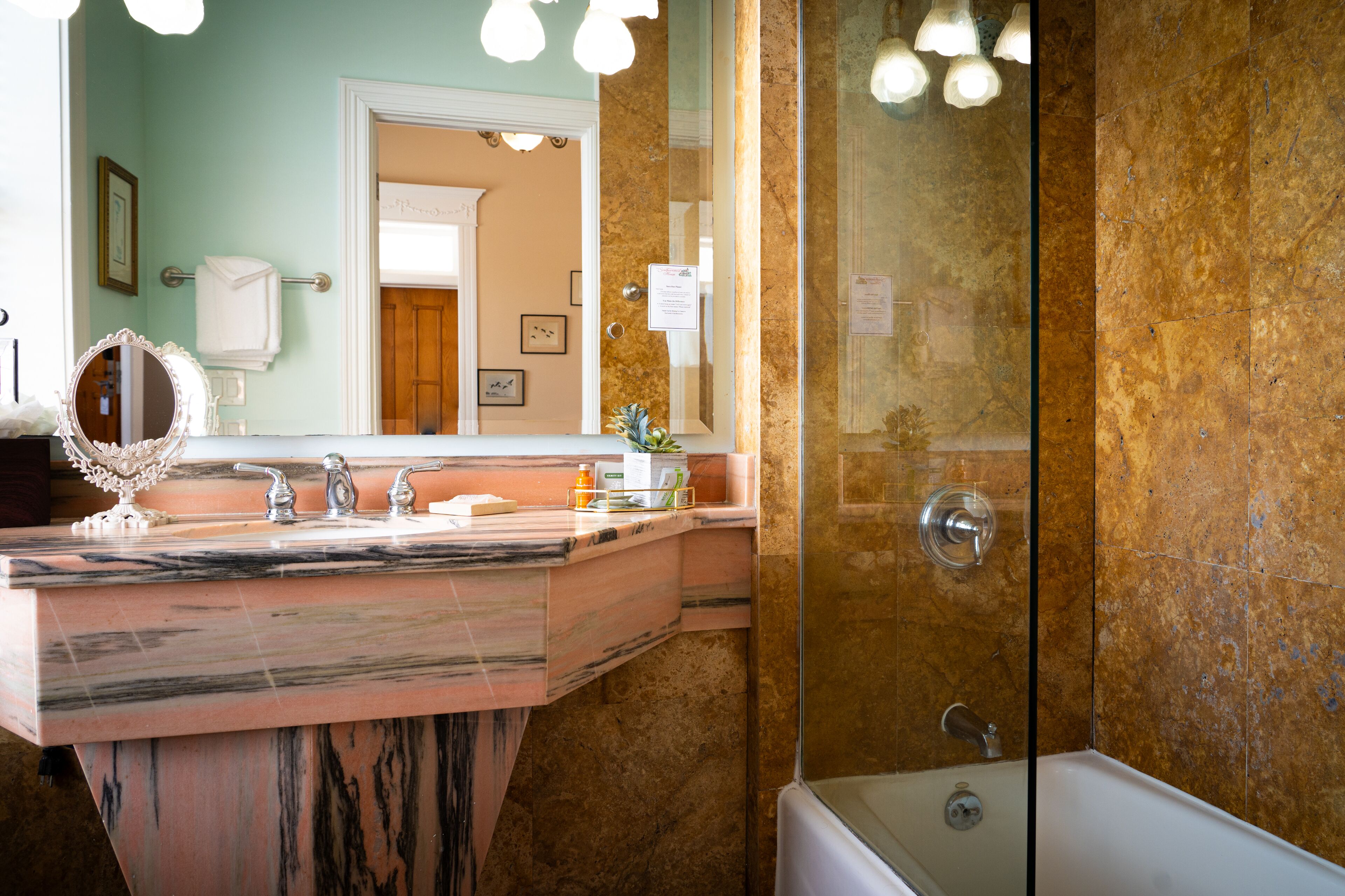 Ein Badezimmer mit Marmorwaschbecken, einer Duschkabine aus Glas und einer weißen Badewanne.