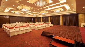 A conference room with rows of white chairs, a large table, and a carpeted floor. - GIS Select Banjara  Hills (Hyderabad)