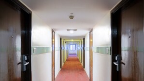 A hotel hallway with a red carpet, wooden doors, and a light-colored wall. - GIS Select Banjara  Hills (Hyderabad)