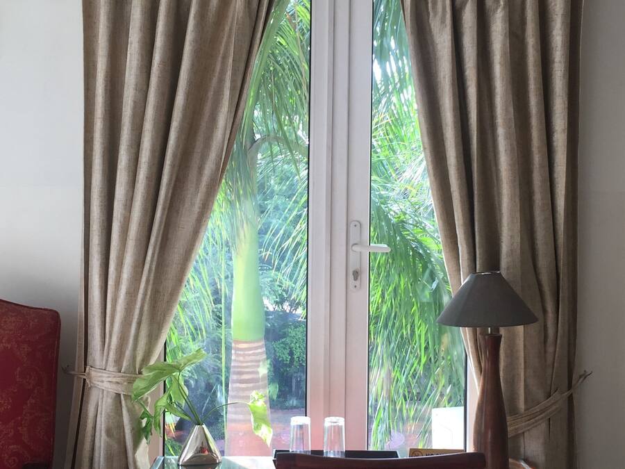 A room with a desk, a chair, a lamp, and curtains.