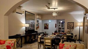 A dining area with a high arched ceiling, a chandelier, and a piano. - Barwara Kothi (Jaipur)