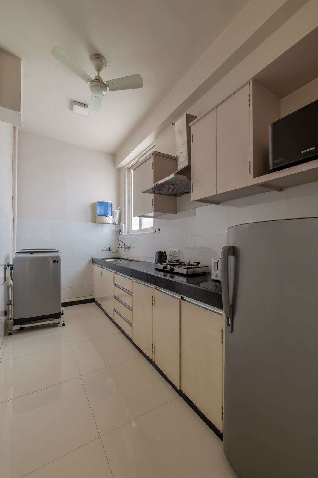 A kitchen with a refrigerator, stove, microwave, and a ceiling fan.