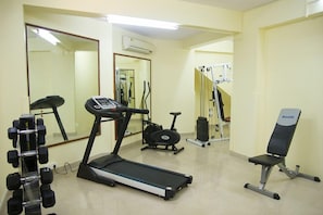 A gym with a treadmill, exercise bike, dumbbells, and a bench. - Nazri Resort (Baga)