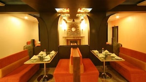 A restaurant with booths and tables, a fireplace, and decorative lighting. - Nazri Resort (Baga)