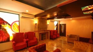 A spacious lounge area with red and beige sofas, a fireplace, and a large window with a view. - Nazri Resort (Baga)