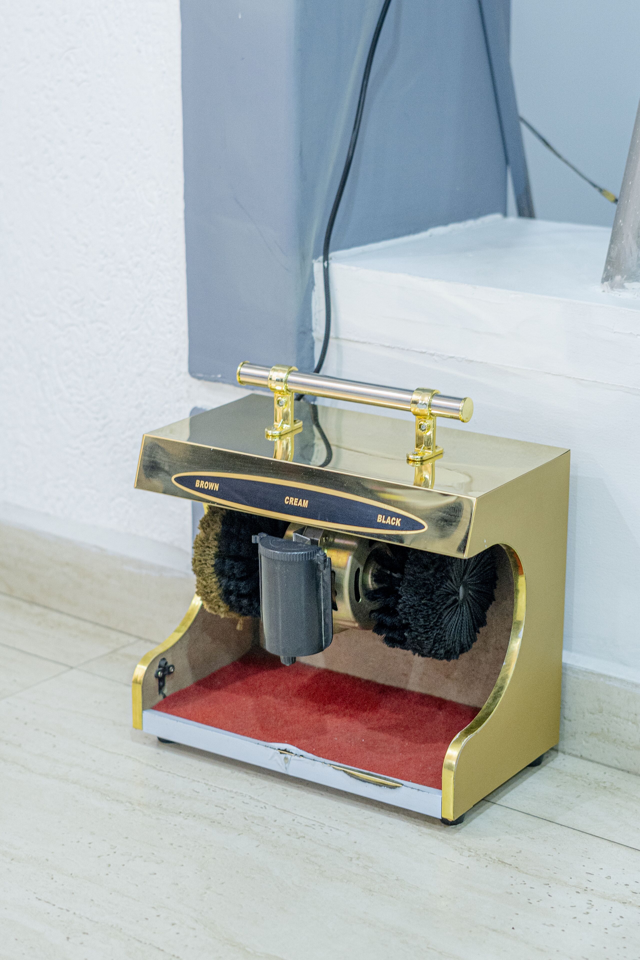 A compact, gold-colored coffee machine with a red interior and a small black container.