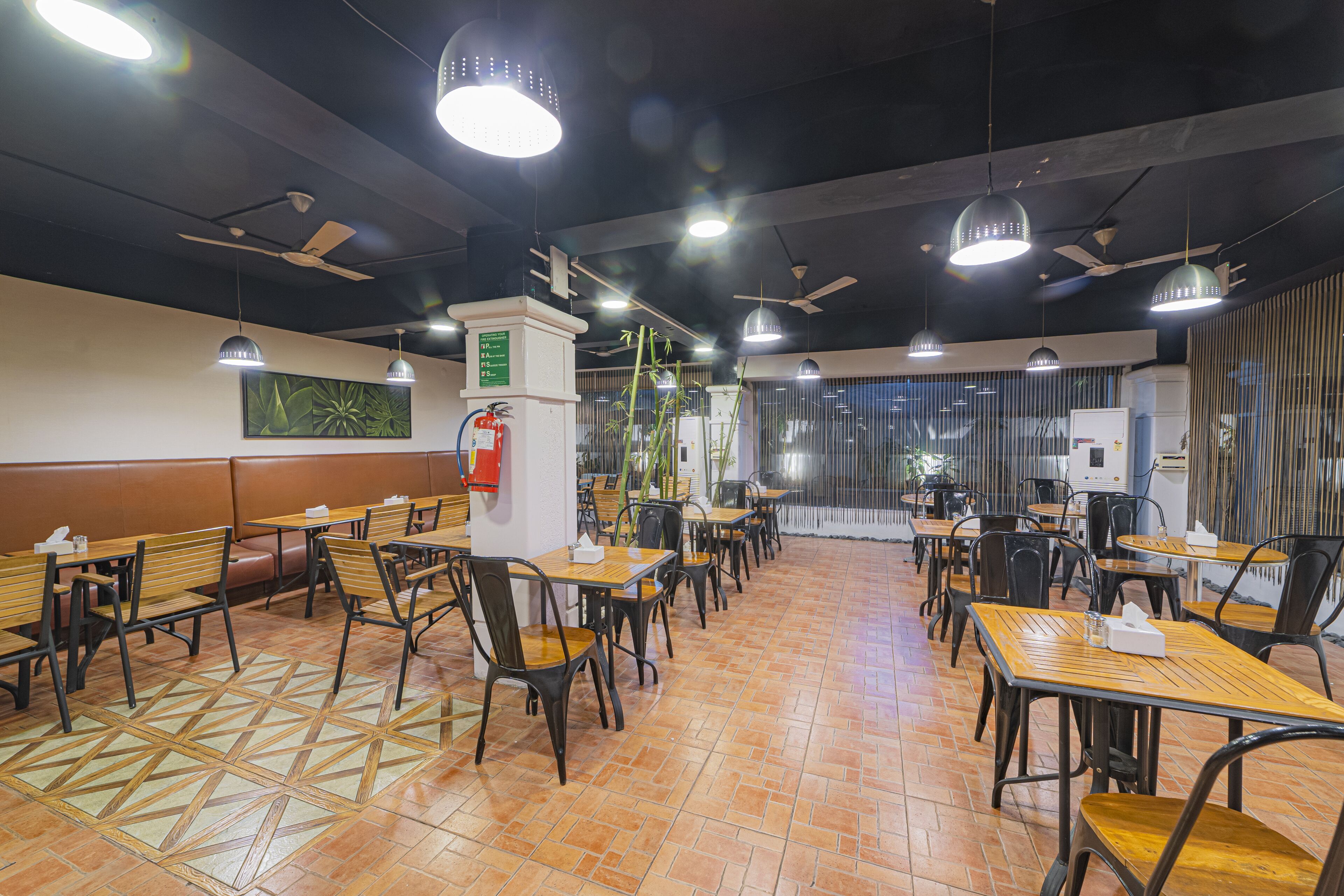 A restaurant with wooden tables and chairs, ceiling fans, and pendant lighting.