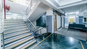 A modern interior with a staircase, a bench, and a fire hose on the wall. - Hotel Athome & Serviced Apartments by Deccan Serai Hotels (Hyderabad)