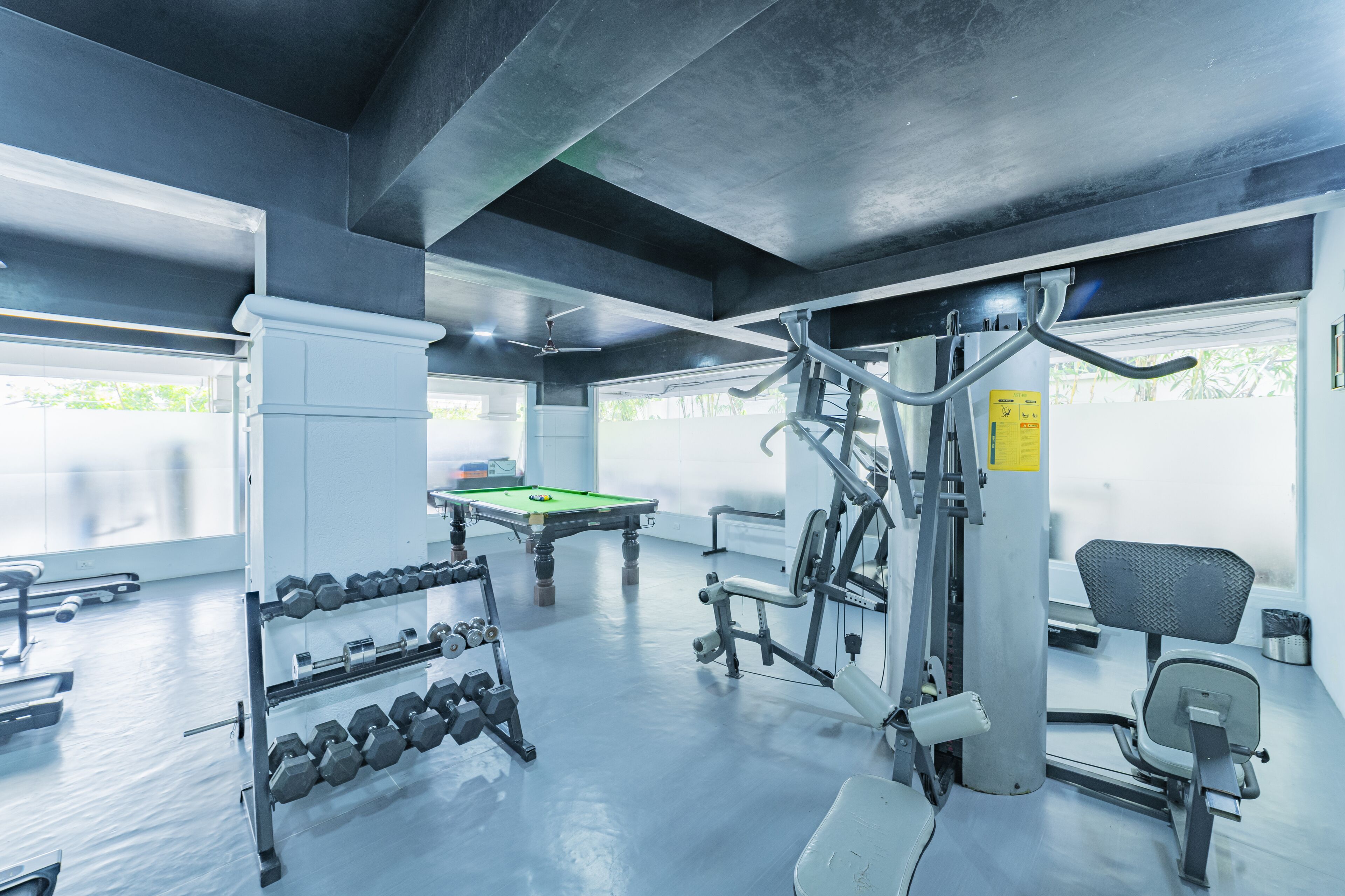 A gym with exercise equipment, a pool table, and a chair.