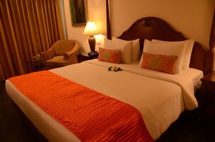 Une chambre d’hôtel avec un grand lit, une chaise, une lampe et une table de chevet.