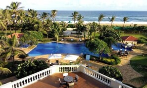 A resort with a large pool, palm trees, and a view of the beach. - The Hans Coco Palms (Puri)