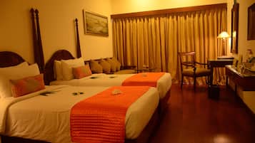 A hotel room with two beds, a desk, a chair, and a large window with curtains.