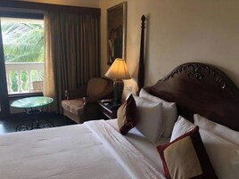 Habitación de hotel con una cama grande, una silla, una mesita y una ventana con cortinas.