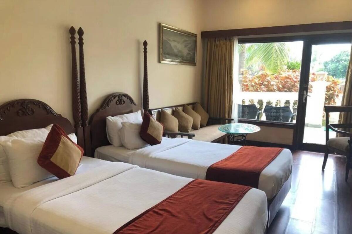 Une chambre d’hôtel avec deux lits, une petite table et une vue sur l’extérieur.