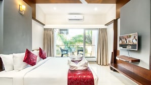 A hotel room with a bed, a TV, a balcony with a table and chairs, and an air conditioning unit. - 7 Apple Resort Lonavala (Mawal)
