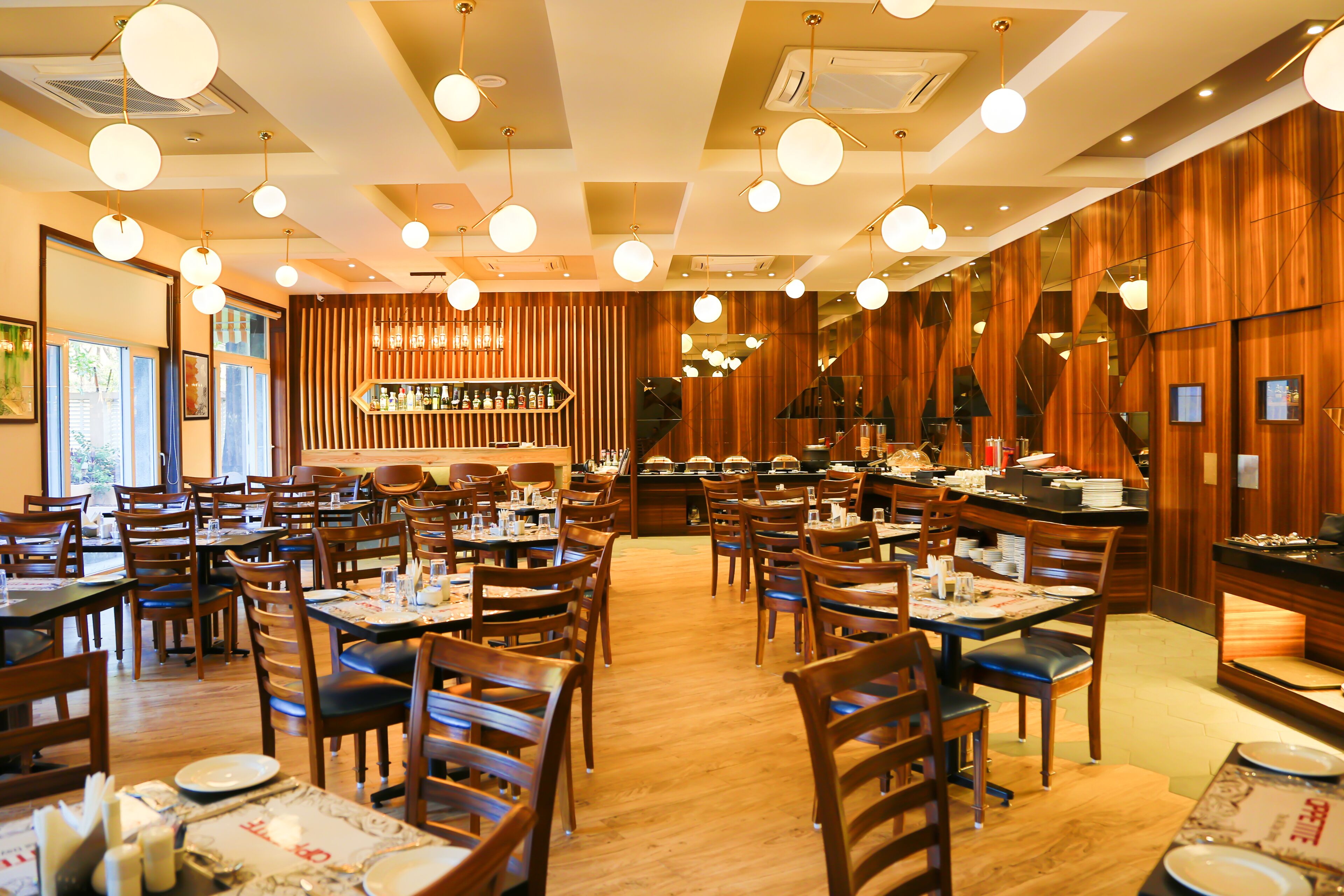 Un restaurante con paredes de paneles de madera, varias mesas para comer y lámparas esféricas colgantes.