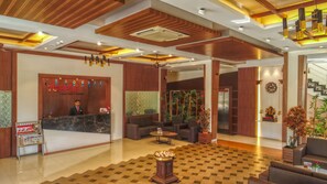 A hotel lobby with a reception desk, seating area, and a staircase. - 7 Apple Resort Lonavala (Mawal)