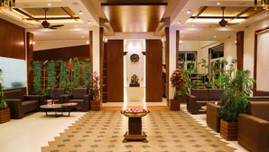 A spacious lobby with a central decorative fountain, comfortable seating areas, and a variety of indoor plants. - 7 Apple Resort Lonavala (Mawal)