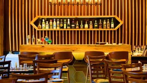 A restaurant with a wooden wall, a bar area with various bottles, and several tables and chairs. - 7 Apple Resort Lonavala (Mawal)