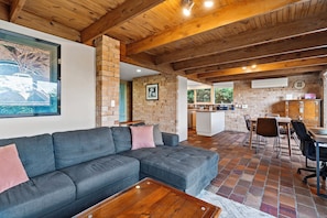 A cozy living area with a sectional sofa, a wooden coffee table, and a kitchen in the background.
