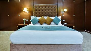 A hotel room with a large bed, a nightstand, a lamp, and a vase with flowers.