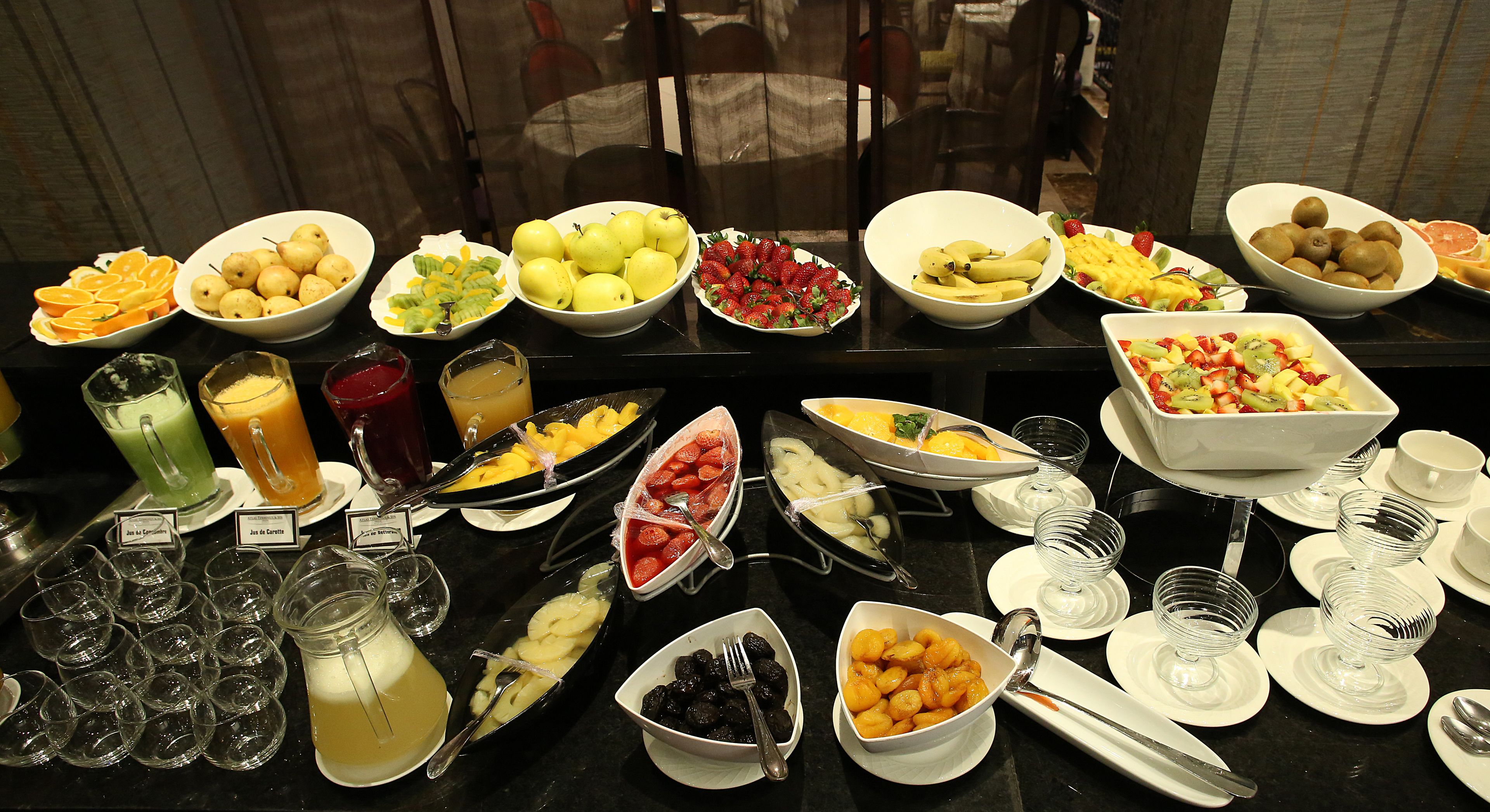 Un bufé con diversas frutas, bebidas y platos.