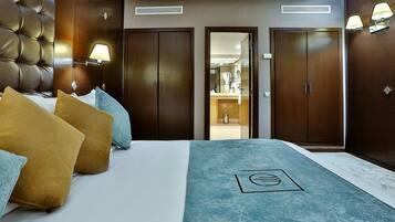 A hotel room with a large bed, two wardrobes, a bathroom visible through an open door, and a wall-mounted lamp.
