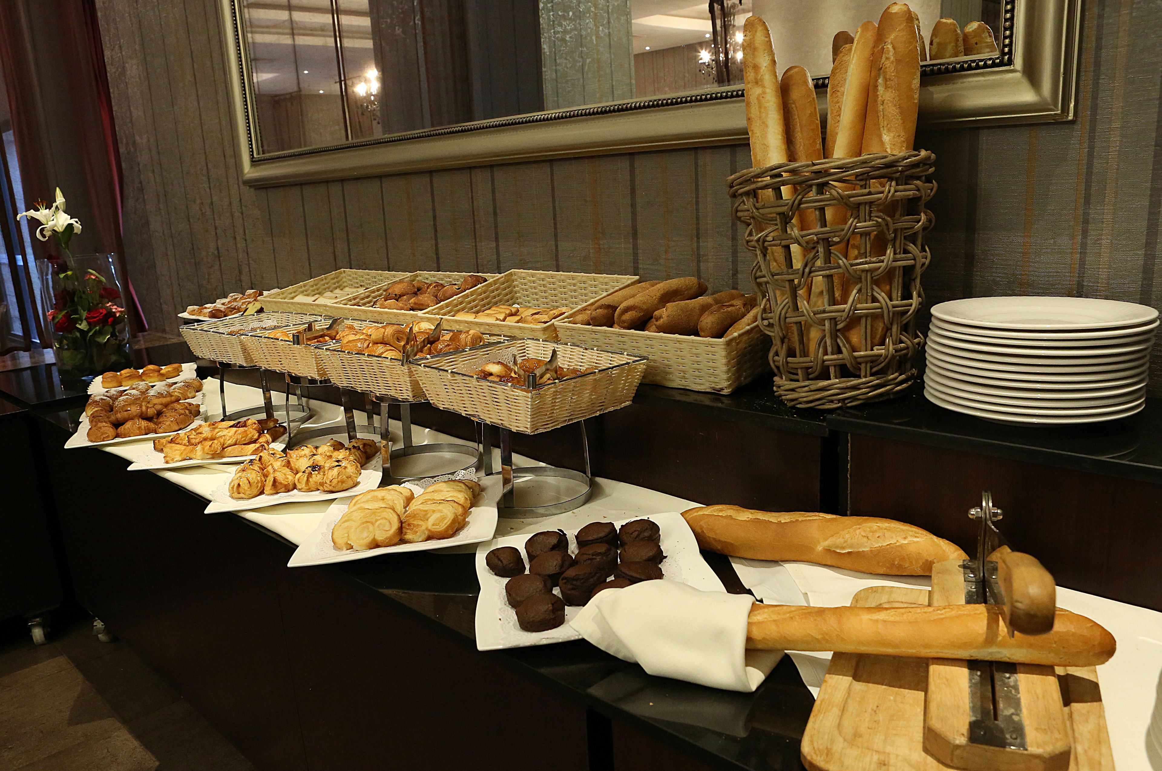 A buffet table with various baked goods and a bread slicer.