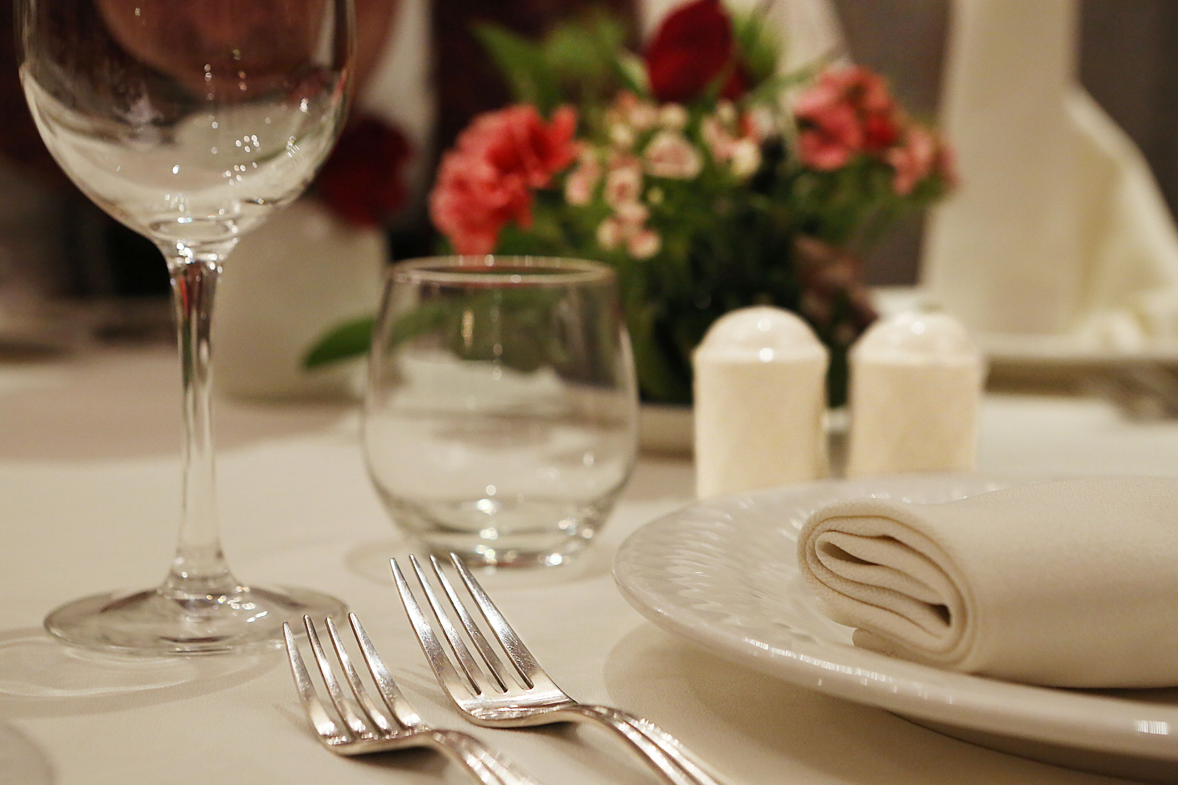 A table set with a folded napkin, a wine glass, a water glass, and a fork.