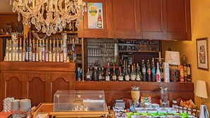 A bar area with a variety of liquor bottles, a chandelier, and a display of food items. - Hostellerie Val Fleuri (Mersch)