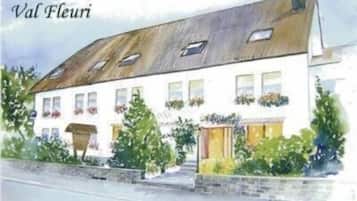 A two-story building with a sloped roof, multiple windows, and a front entrance.