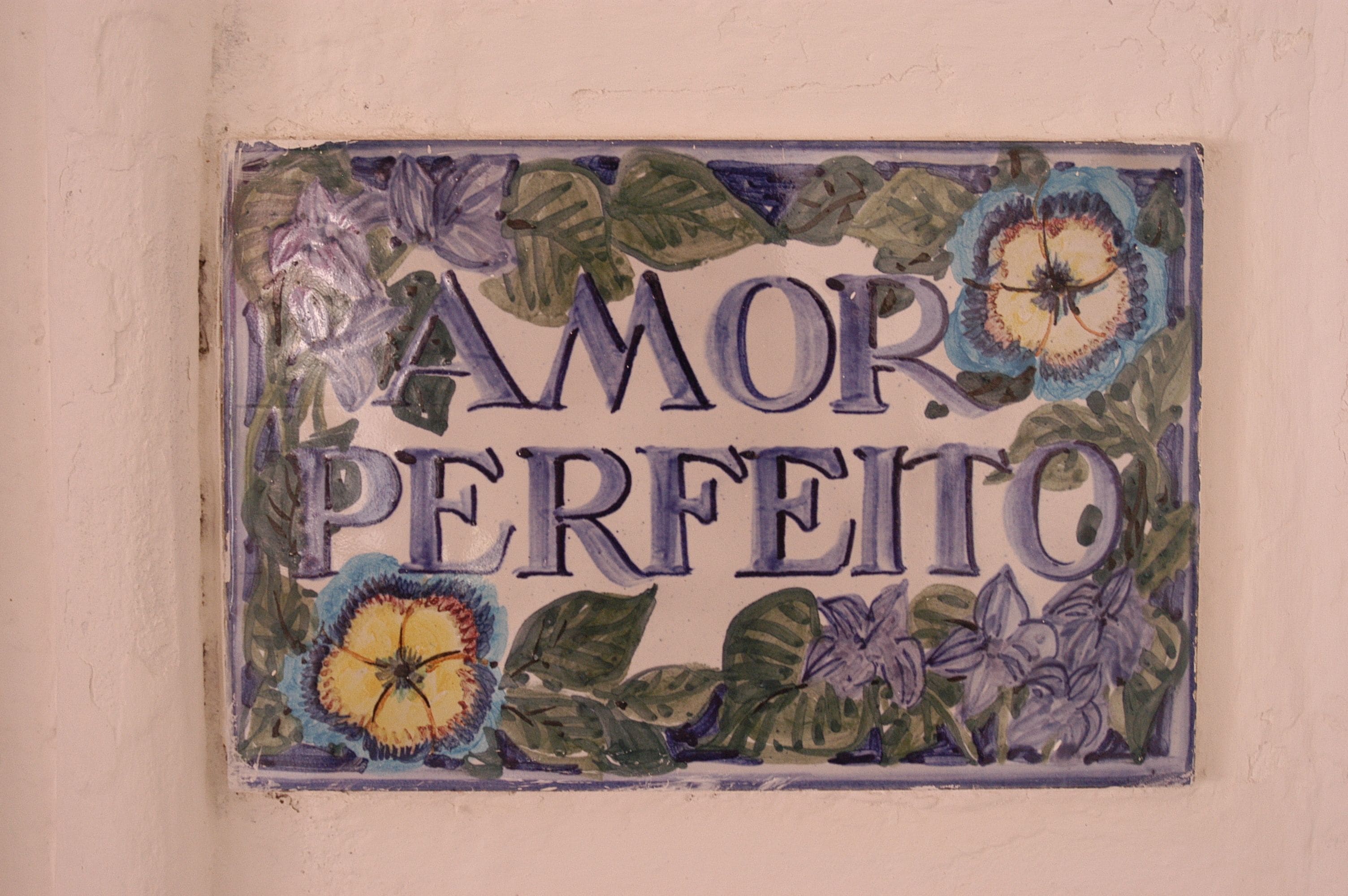 Una baldosa decorativa con las palabras "AMOR PERFECTO" rodeadas de motivos florales.