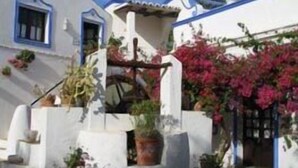Um edifício branco com detalhes em azul e uma pequena varanda com vasos de plantas.