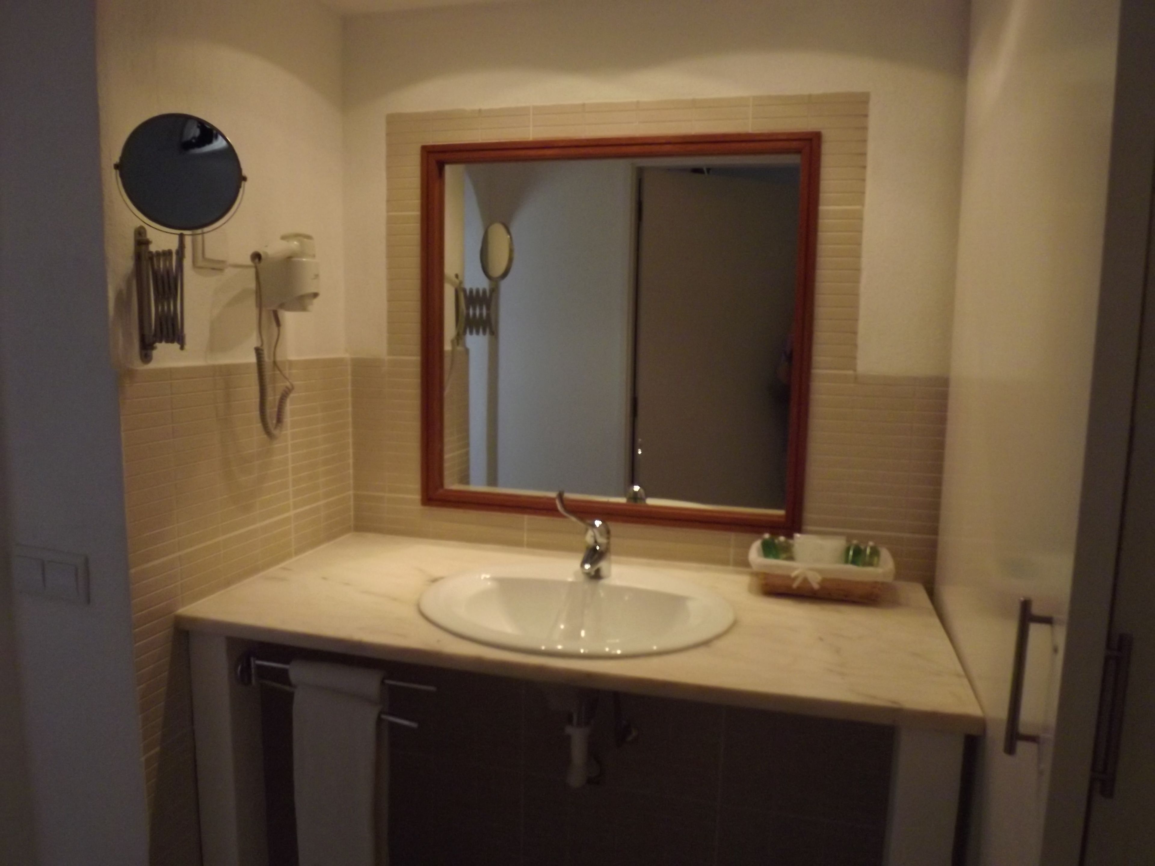 A bathroom with a white sink, a mirror with a wooden frame, and a towel rack.