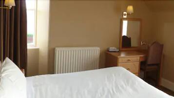 Une chambre d’hôtel avec un lit, un bureau, une chaise, un miroir et une fenêtre.