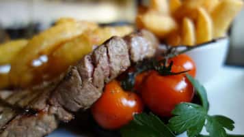 Un plato con bistec en rodajas, tomates cherry y papas fritas.