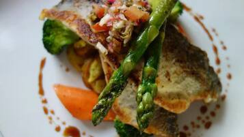 A plate of food with grilled fish, asparagus, and a tomato-based sauce.