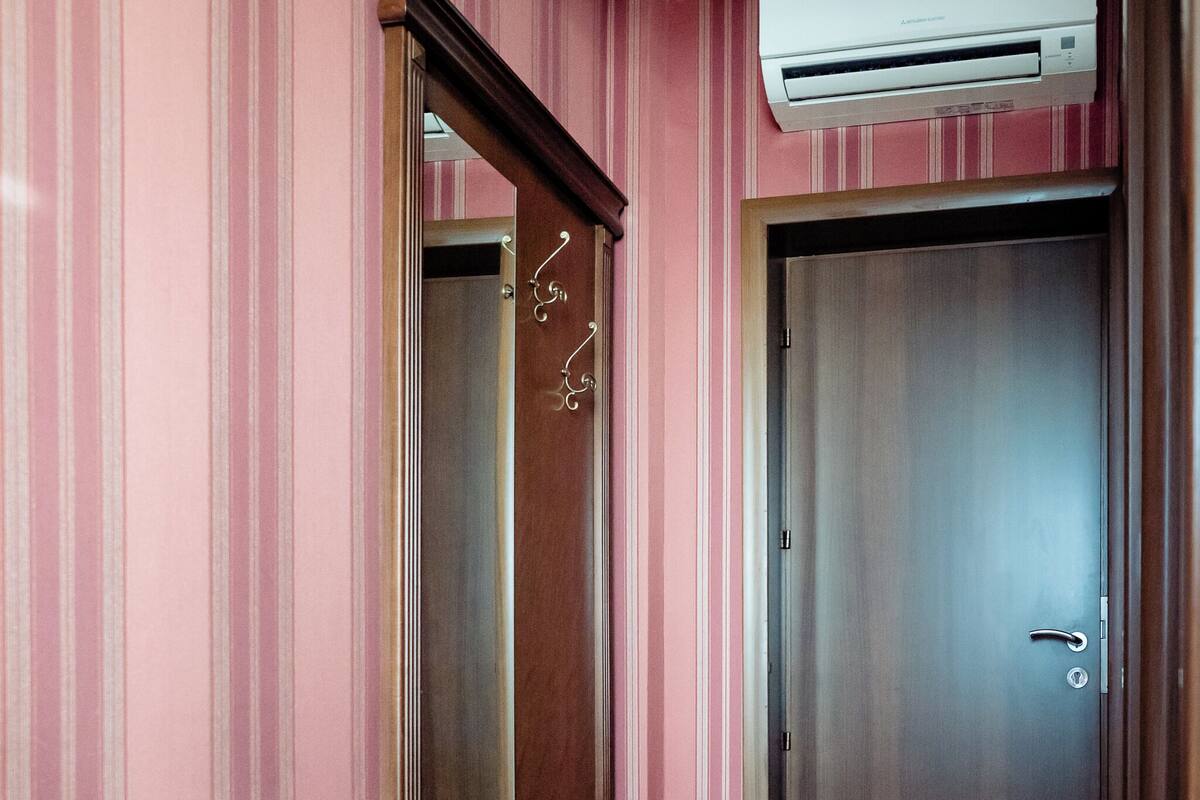 A room with a wooden bench, a large mirror, a wardrobe, and a door.