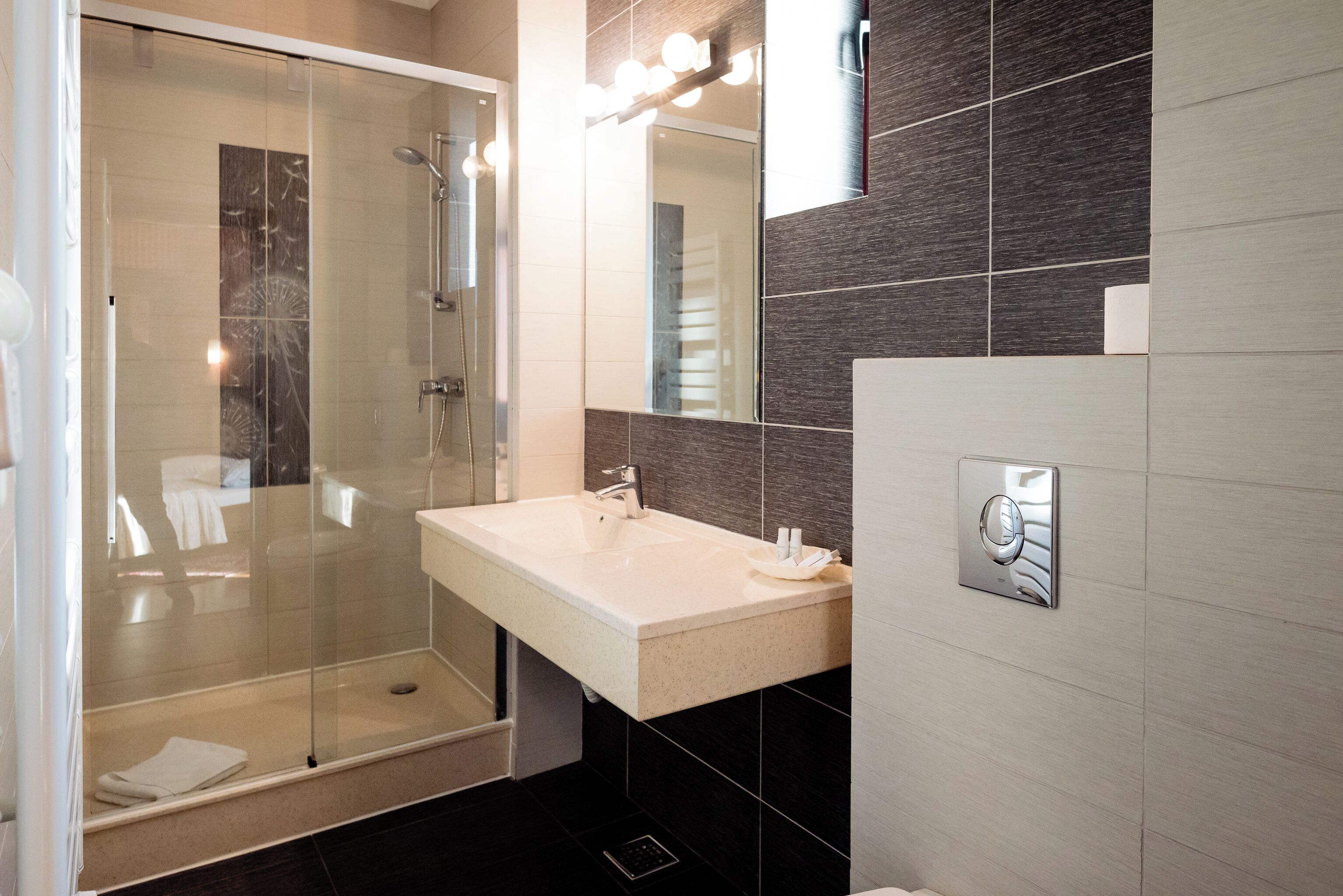 Une salle de bain moderne avec une douche à parois de verre, un lavabo avec un miroir et un porte-serviettes.