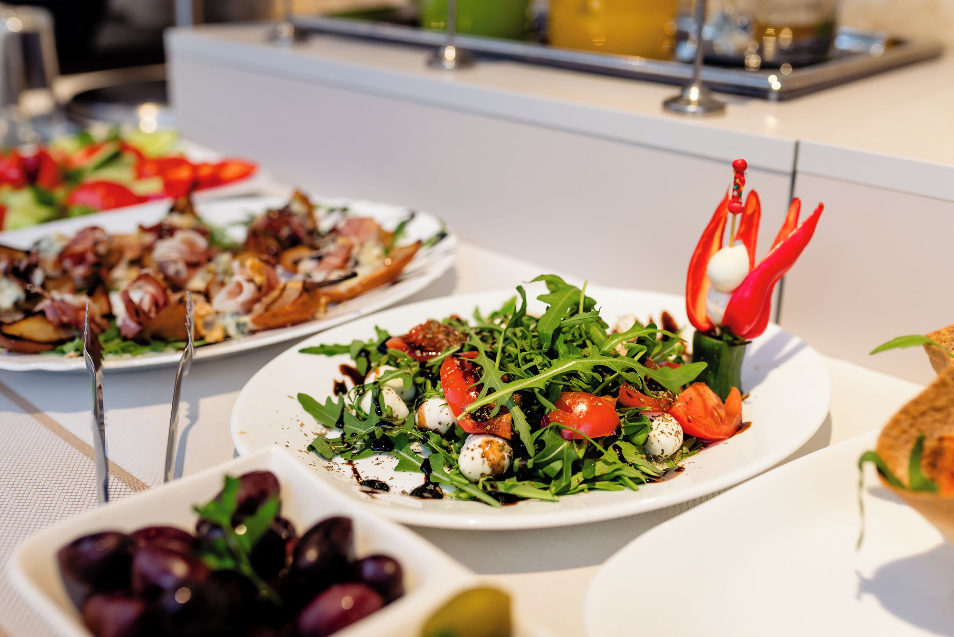 Un buffet proposant divers plats, notamment des salades, des grillades et un saladier d’olives.