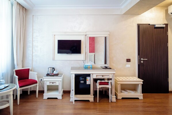 Habitación de hotel compacta con escritorio, silla y un pequeño refrigerador.