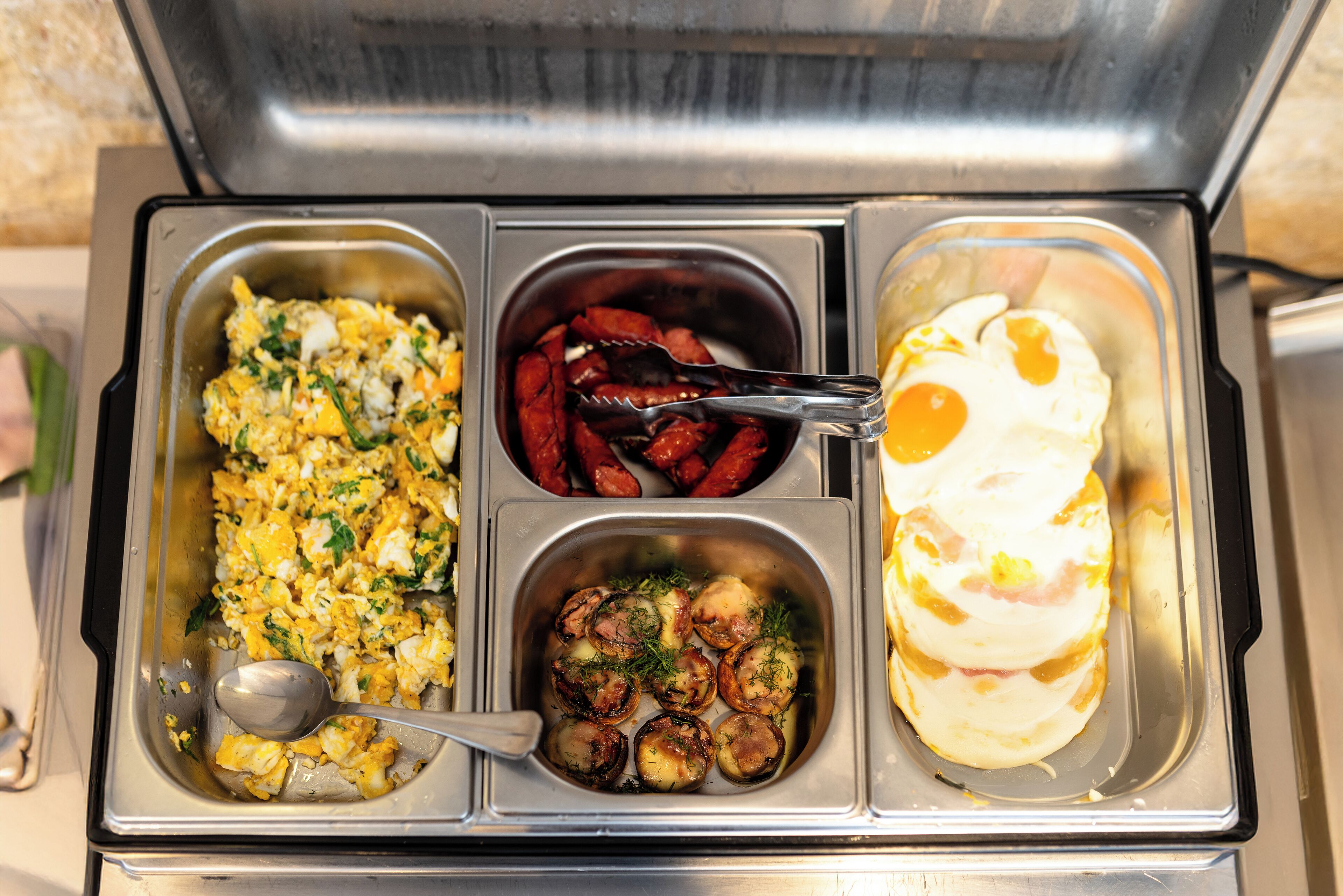 A buffet with scrambled eggs, red peppers, and omelets.