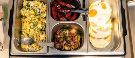 A buffet with scrambled eggs, red peppers, and omelets.