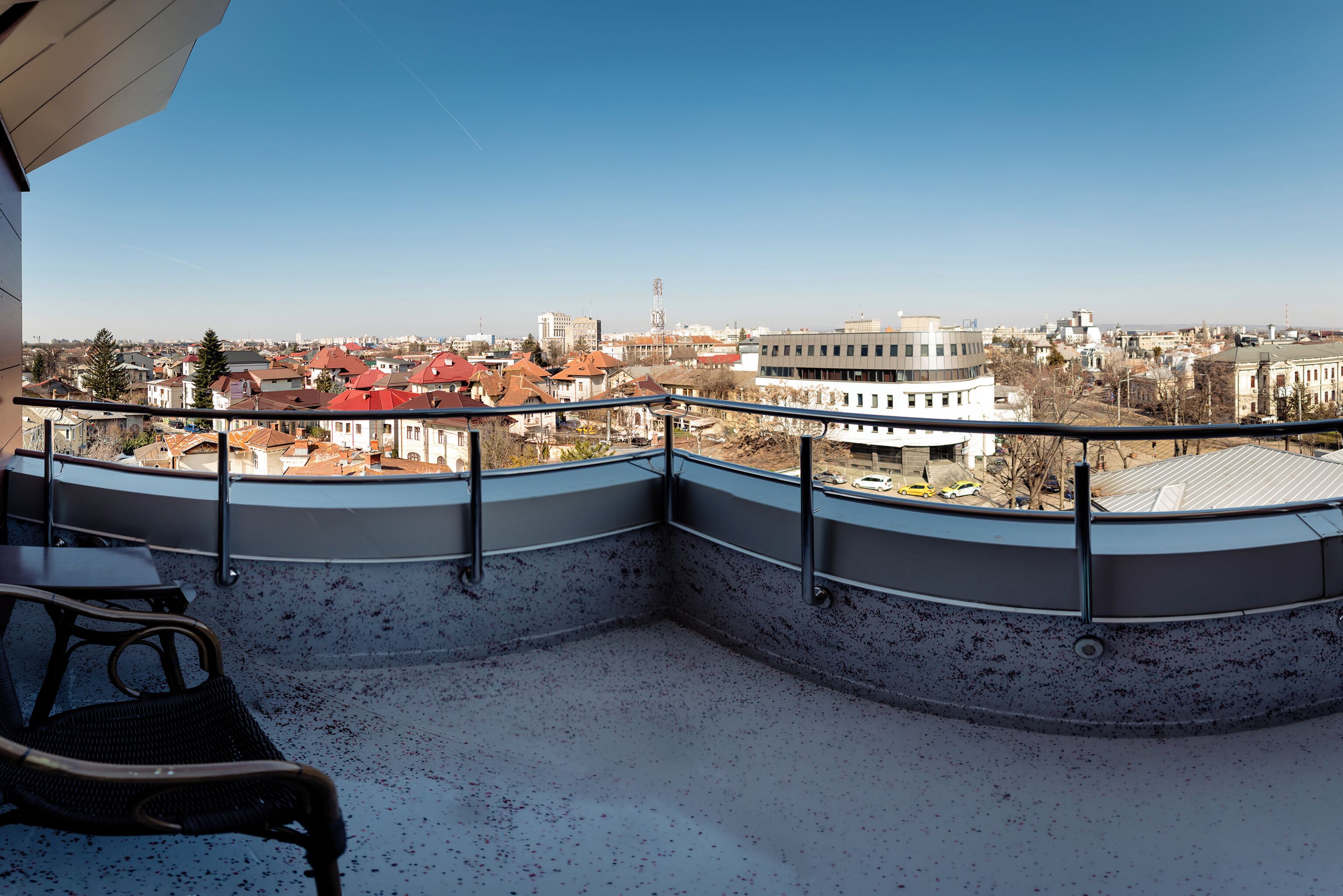 A balcony with a view of a cityscape, including buildings and a clear sky.