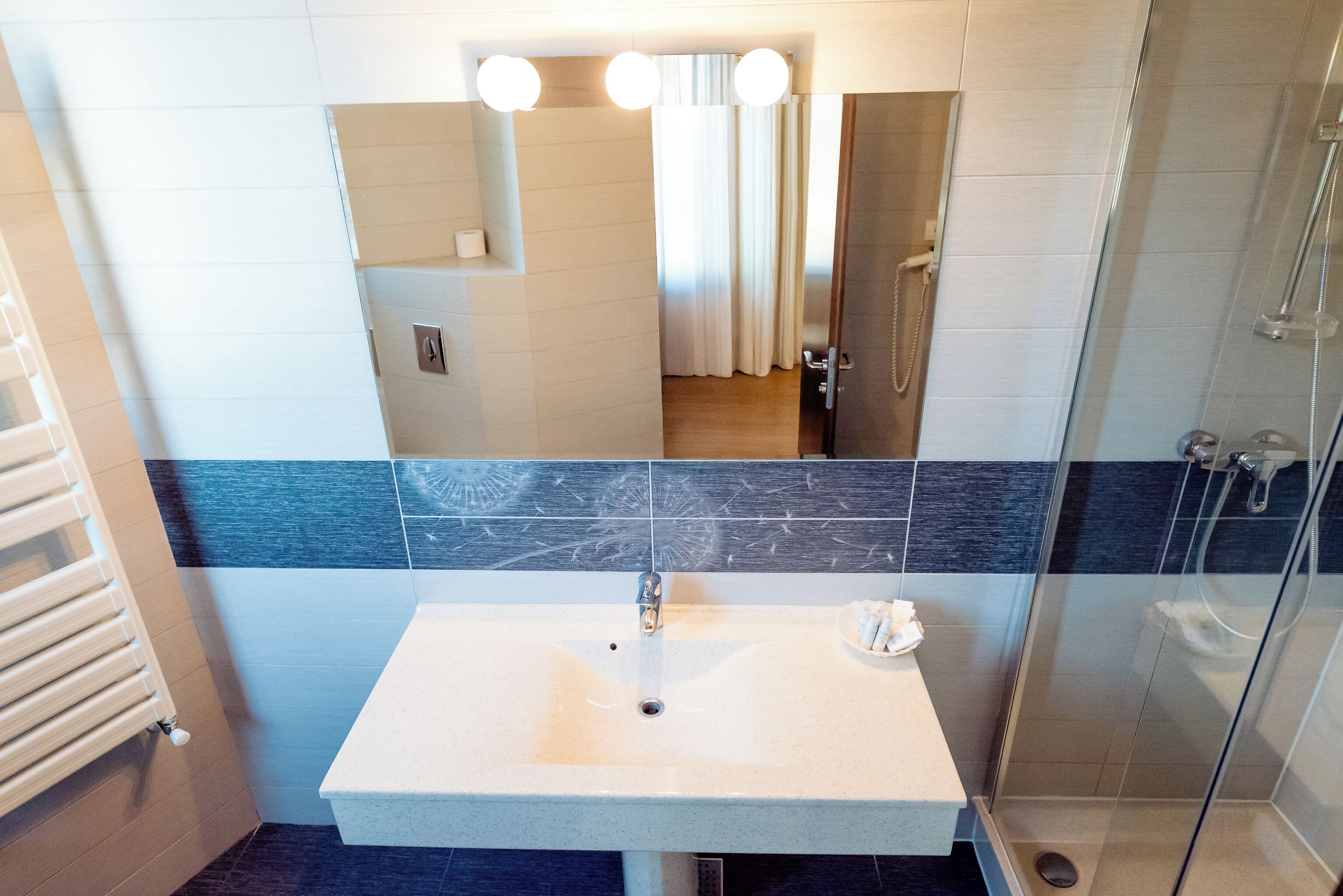 A bathroom with a white sink, a mirror, and a shower.