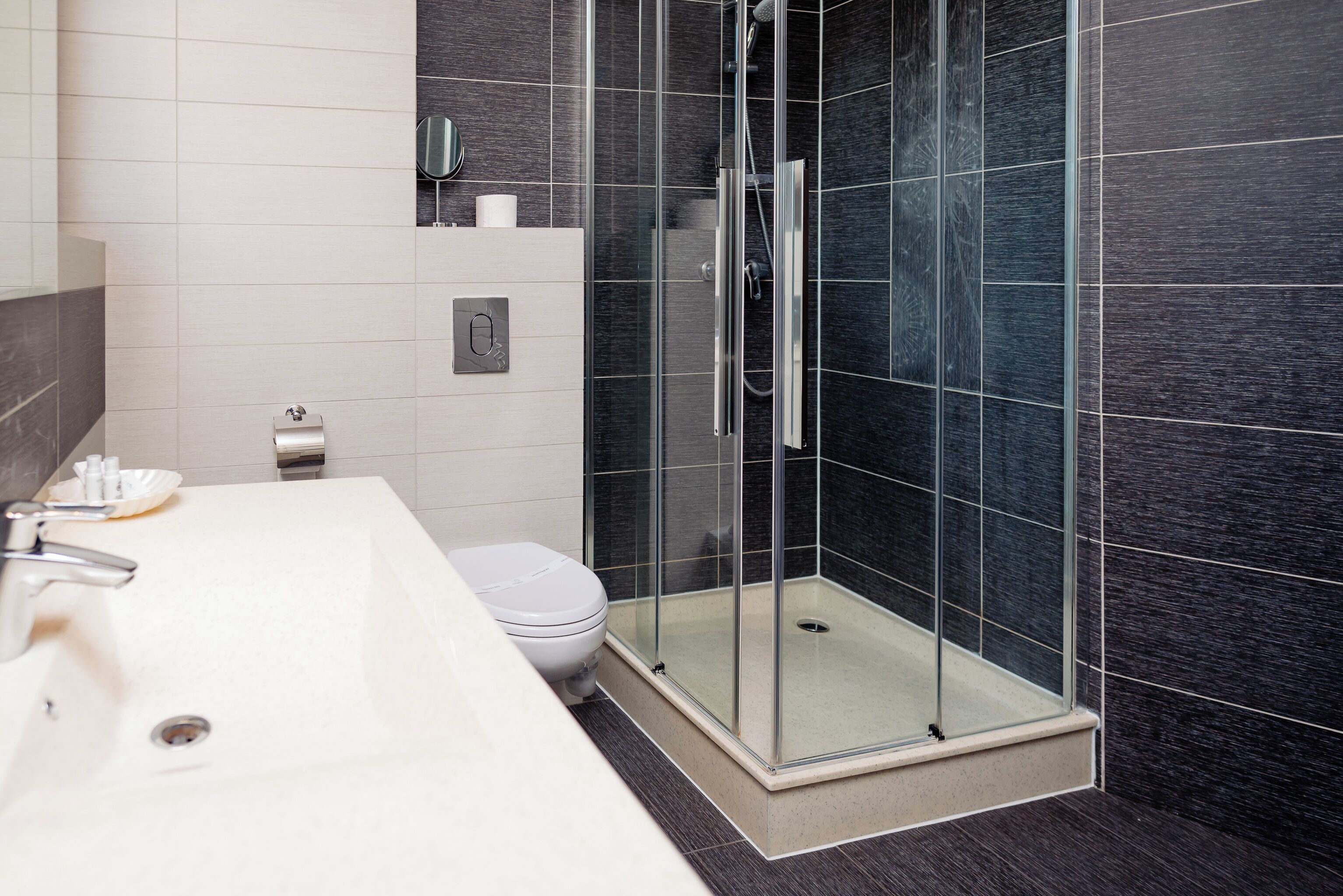 A modern bathroom with a glass-enclosed shower, a white sink, and a toilet.
