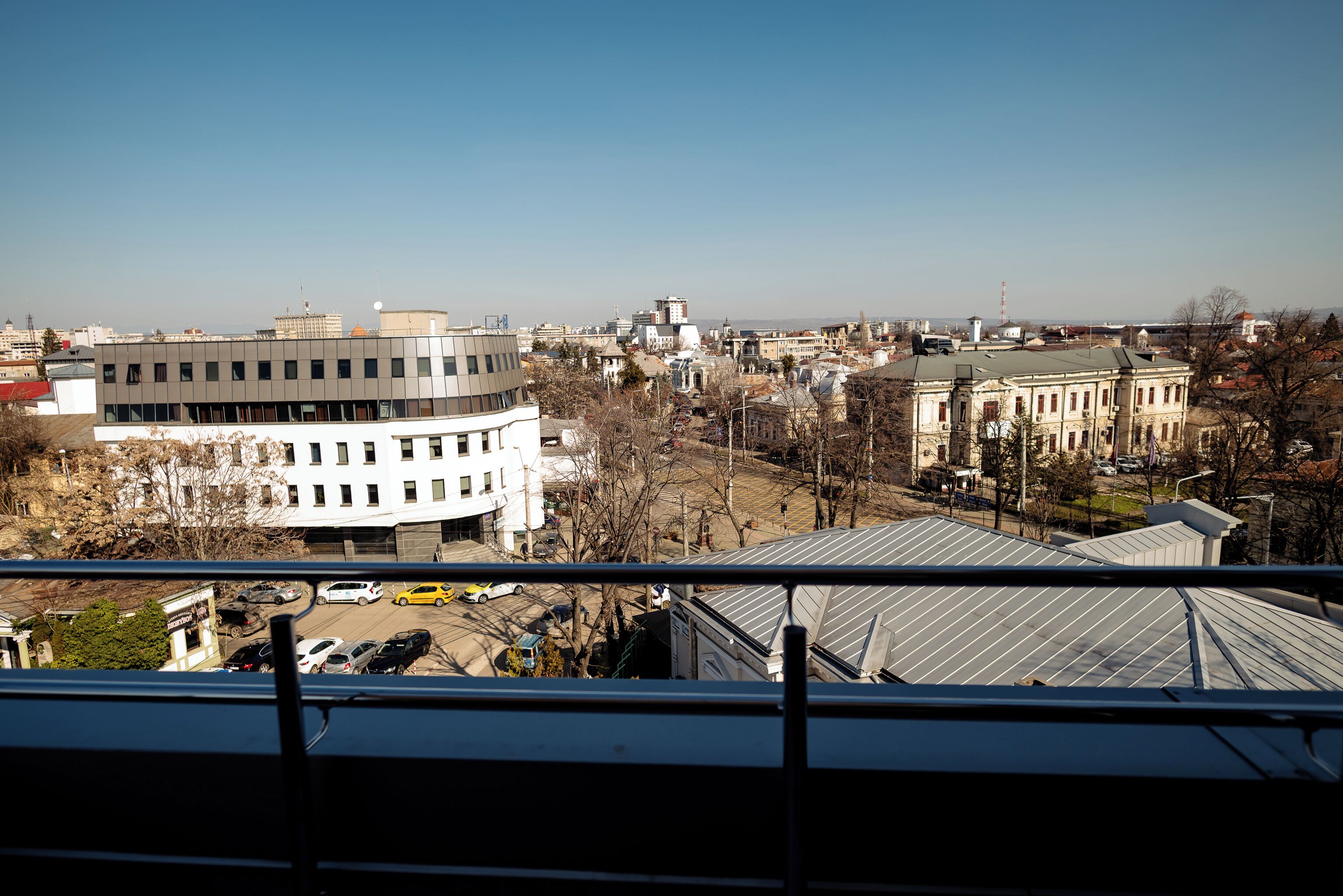 A cityscape with a mix of modern and historical buildings, including a prominent white building with a curved facade and a large, ornate building with a green roof.