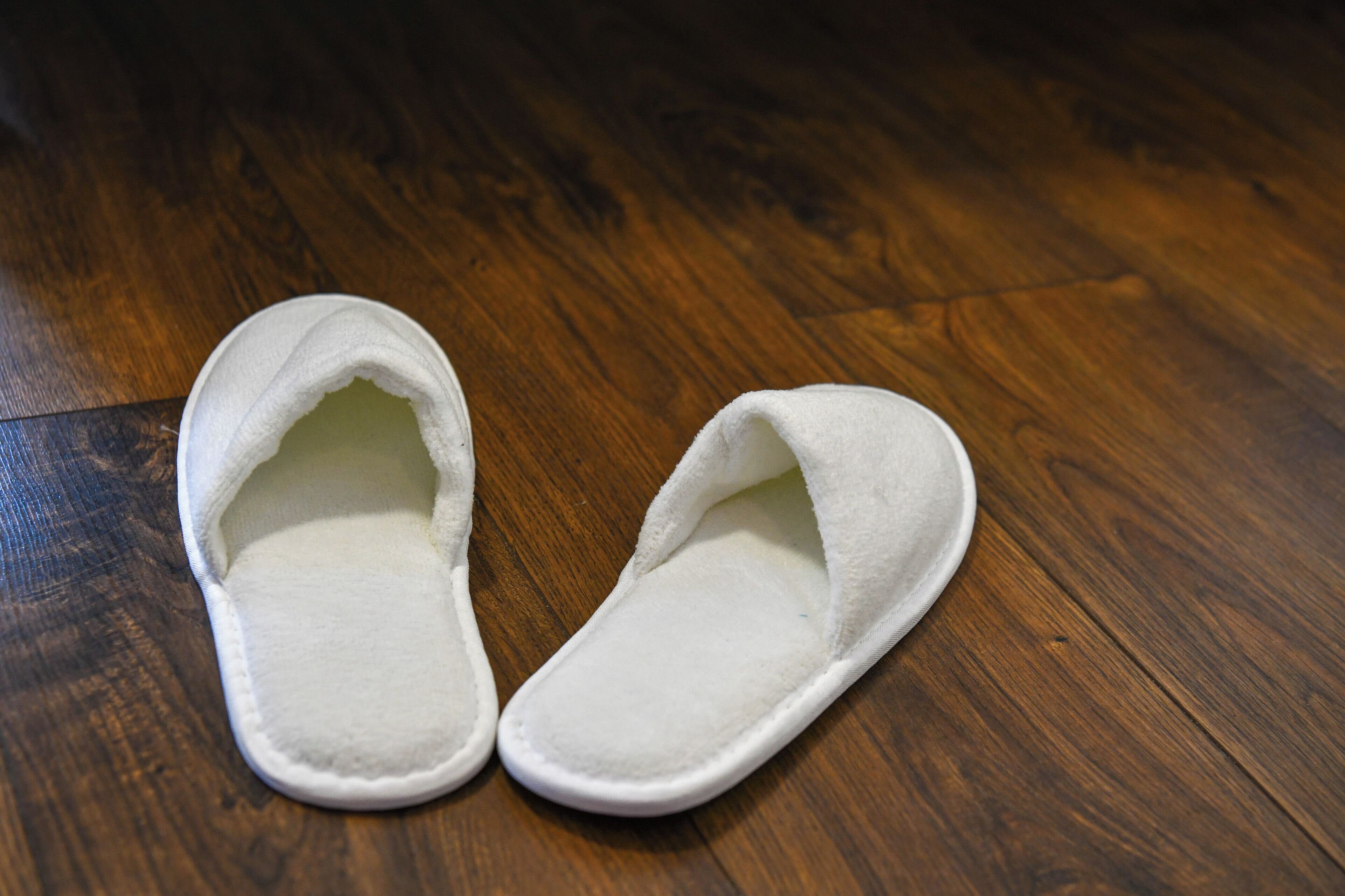 Une paire de pantoufles blanches sur un plancher en bois.