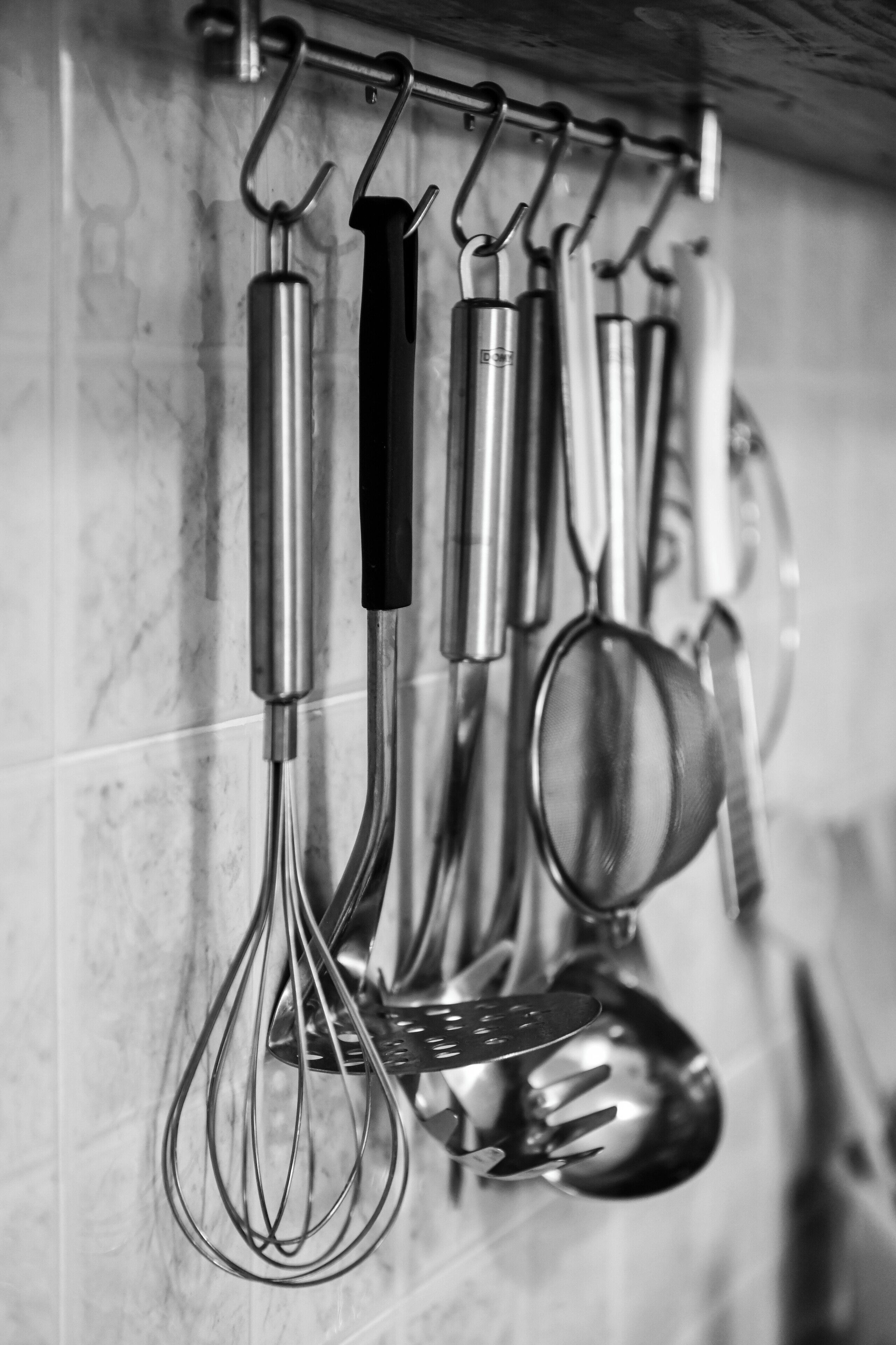A kitchen with various utensils hanging on a rack.