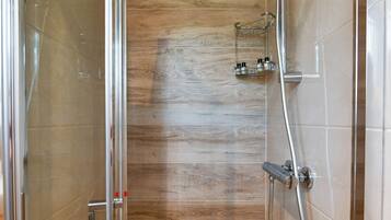 A glass-enclosed shower with a wooden panel wall, a handheld showerhead, and a wall-mounted faucet.